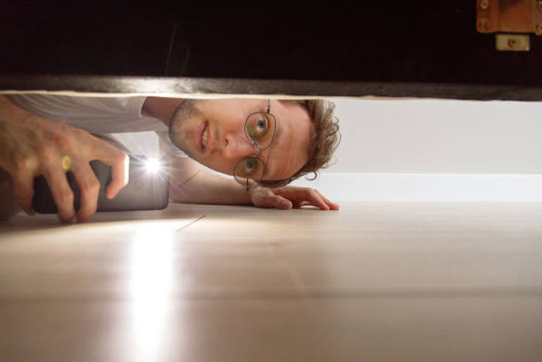 man searching under bed